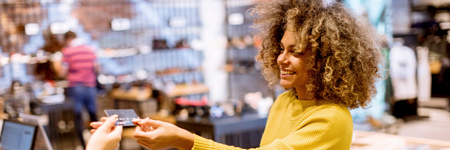 A shopper handing a credit card to a cashier in a retail store.