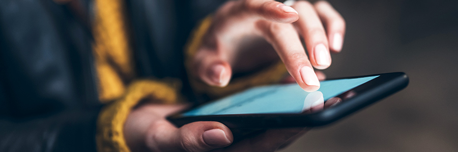 A close-up image a person using a smartphone device, touching it with their finger.
