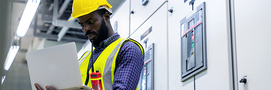Homme à l’intérieur d’une centrale électrique consultant un ordinateur portable.