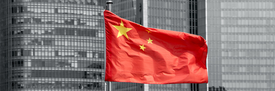 Le drapeau chinois flotte au sommet d’un mât avec des immeubles de bureaux en arrière-plan.