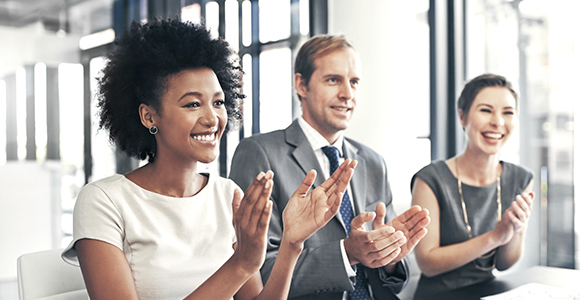 Un groupe de professionnels souriant et applaudissant.