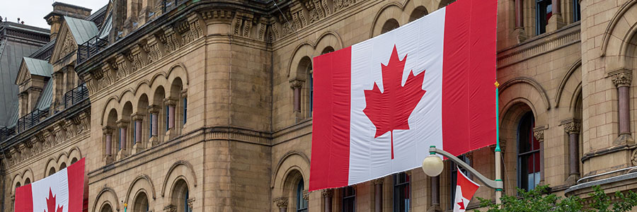 Grand drapeau canadien déployé à l’extérieur d’un immeuble gouvernemental.