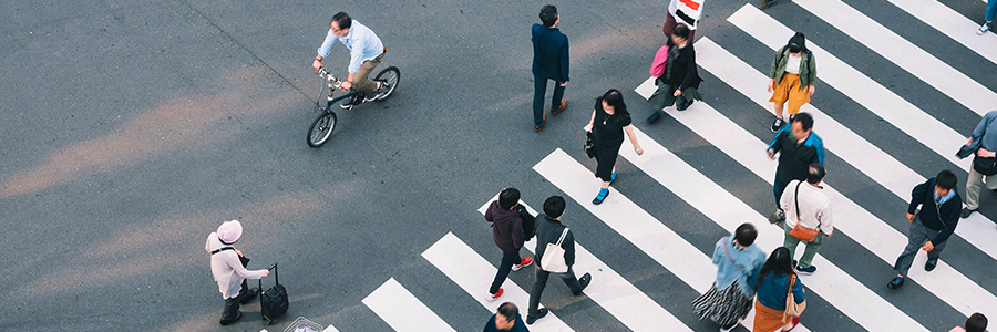 Une foule de personnes traversent la rue dans une ville achalandée.