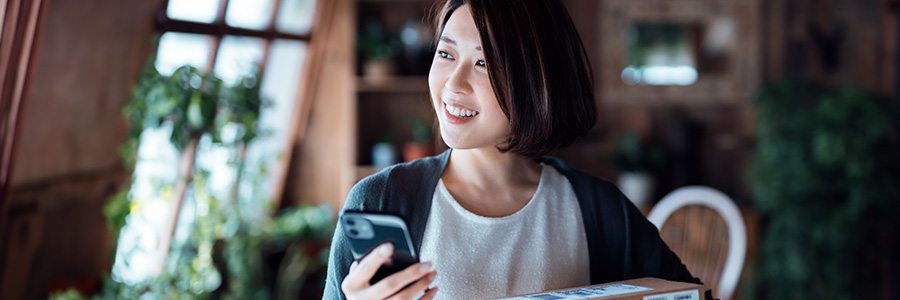 Une femme qui tient un téléphone intelligent et des colis postaux