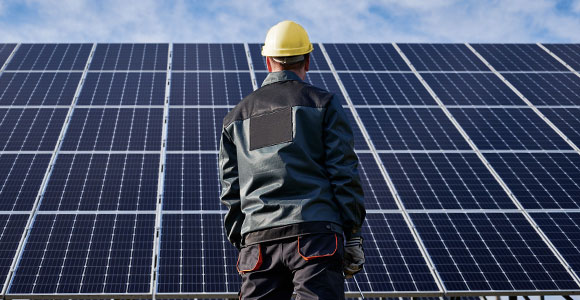 Un homme debout devant des rangées de panneaux solaires. 