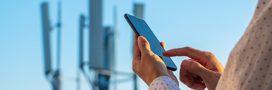 Une personne sur son téléphone intelligent, avec des tours de téléphonie cellulaire en arrière-plan