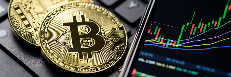 A Bitcoin coin beside trading price charts